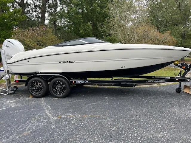 Slide: The Image of 2024 Stingray 230SX boat on trailer, parked outdoors. - 1