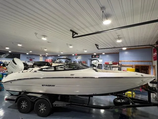Slide: The Image of 2024 Stingray 230SX boat displayed indoors on a trailer. - 3