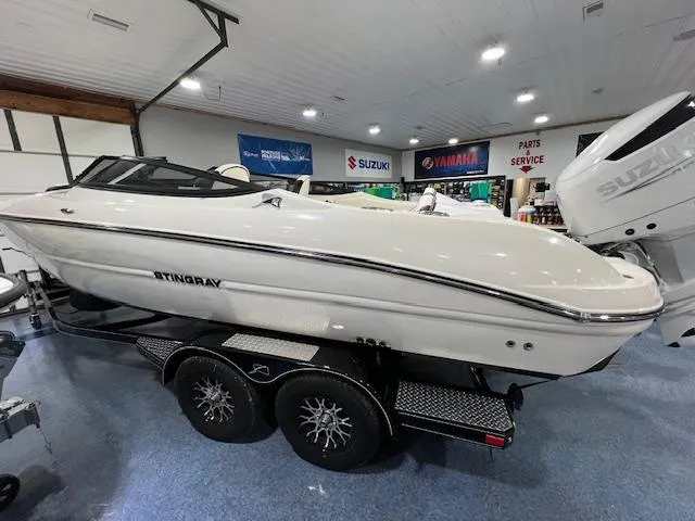 Slide: The Image of 2024 Stingray 230SX boat on a trailer in a showroom with Suzuki and Yamaha signage. - 9