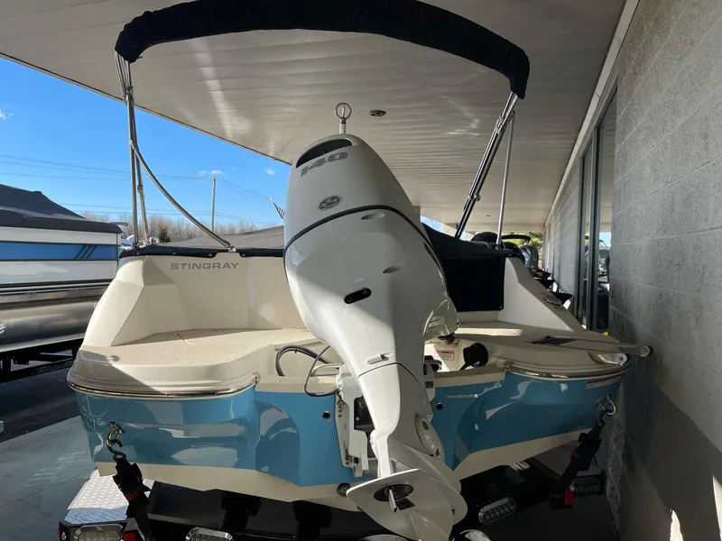 Slide: The Image of 2024 Stingray 192 SC boat with outboard motor, blue and white design, under a covered area. - 10