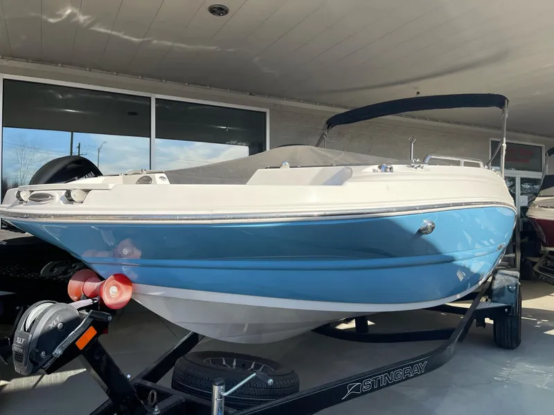 Slide: The Image of 2024 Stingray 192 SC boat in blue and white on a trailer, displayed outdoors. - 12