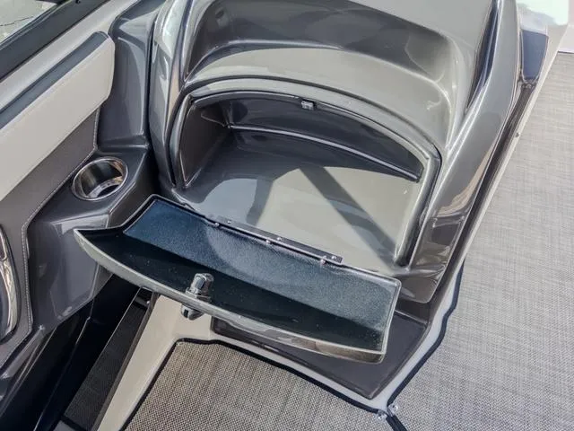 Slide: The Image of 2024 Monterey 258 SS boat storage compartment with open lid and cup holder. - 26