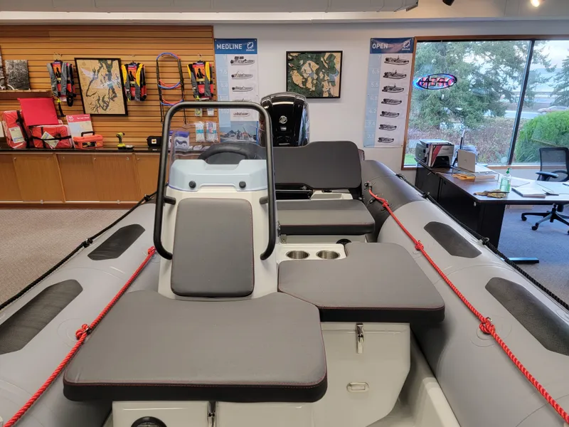 Slide: The Image of 2024 Zodiac Open 4.8 boat interior with seating and console in showroom. - 10