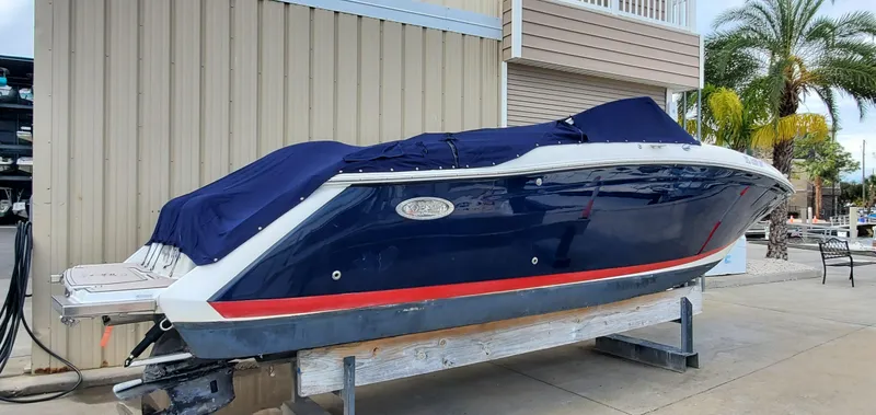 Slide: The Image of 2013 Cobalt 24SD boat with blue cover, docked near a palm tree and building. - 10