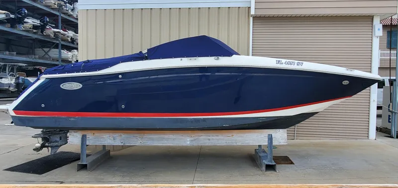 Slide: The Image of 2013 Cobalt 24SD boat with blue hull and red stripe, stored on a lift. - 12