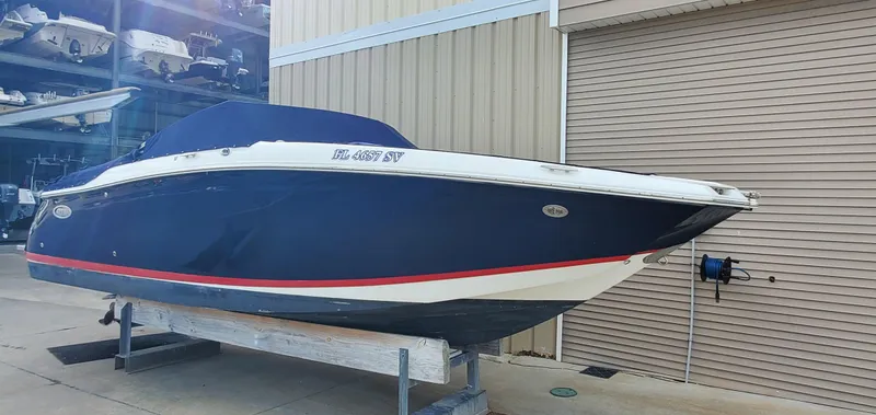 Slide: The Image of 2013 Cobalt 24SD boat with blue cover, docked near storage facility. - 13
