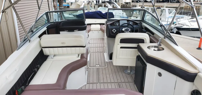 Slide: The Image of 2013 Cobalt 24SD boat interior with seating, steering wheel, and sink, docked at marina. - 19