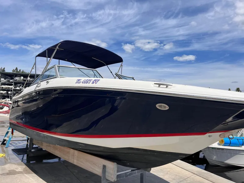 Slide: The Image of 2013 Cobalt 24SD boat with blue hull and canopy, docked under a clear sky. - 2