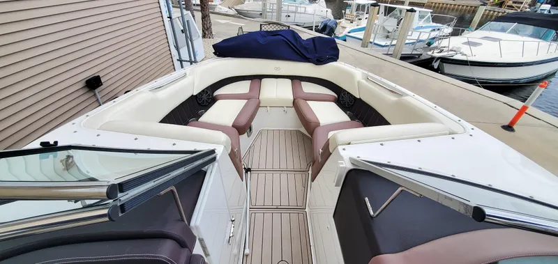 Slide: The Image of 2013 Cobalt 24SD boat interior with cushioned seating and docked boats in the background. - 35