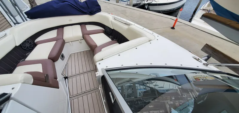 Slide: The Image of 2013 Cobalt 24SD boat interior with brown and white seating at a marina. - 36