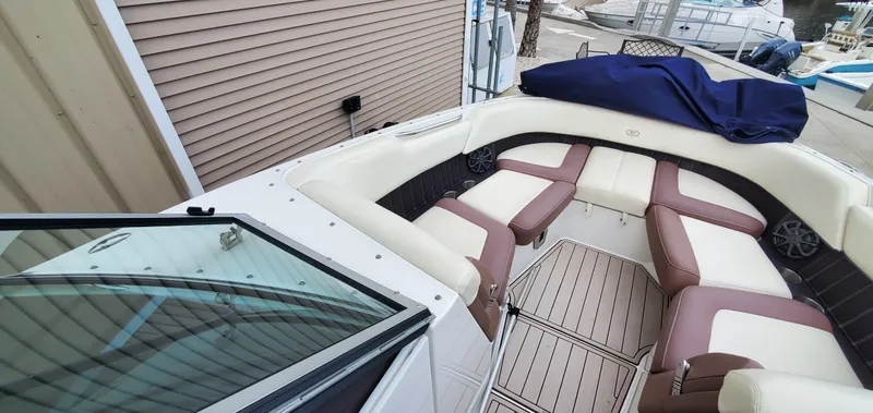 Slide: The Image of 2013 Cobalt 24SD boat interior with beige and brown seating, docked near other boats. - 37