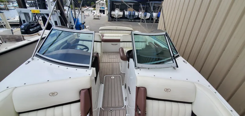 Slide: The Image of 2013 Cobalt 24SD boat interior with white and brown seating at a marina. - 41