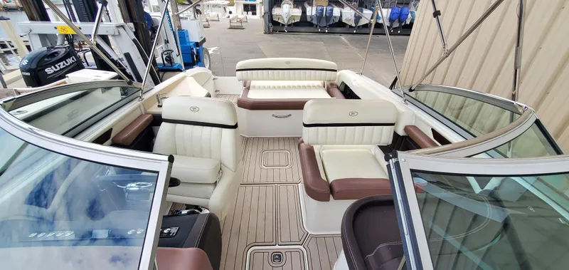 Slide: The Image of 2013 Cobalt 24SD boat interior with white and brown seating, docked near other boats. - 44