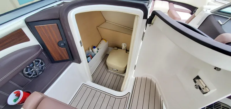 Slide: The Image of 2013 Cobalt 24SD boat interior with open storage compartment and visible cleaning supplies. - 46