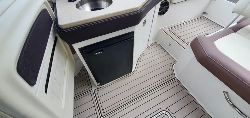 Slide: The Image of 2013 Cobalt 24SD boat interior with sink, mini fridge, and cushioned seating. - 48