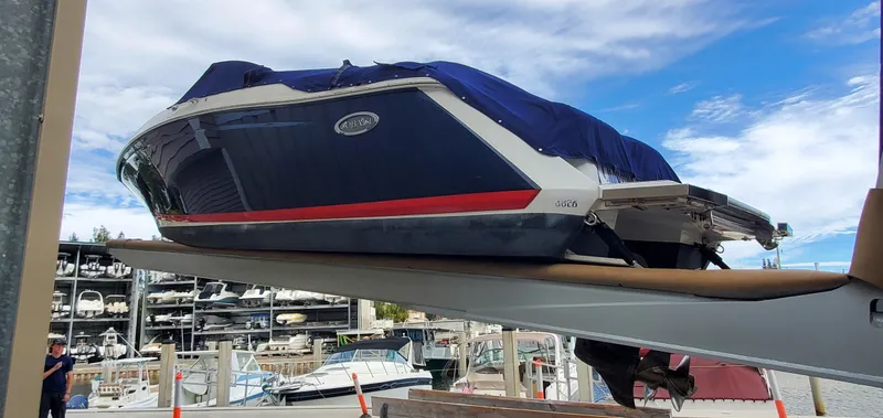 Slide: The Image of 2013 Cobalt 24SD boat on lift at marina, blue cover, clear sky background. - 9
