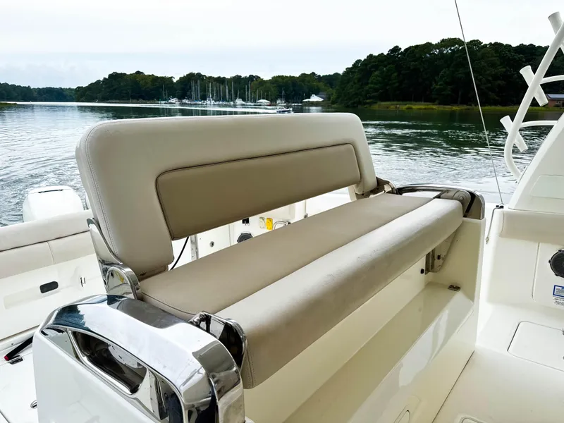 Slide: The Image of 2017 Boston Whaler 420 Outrage boat interior with cushioned seating, docked by a serene lake. - 30