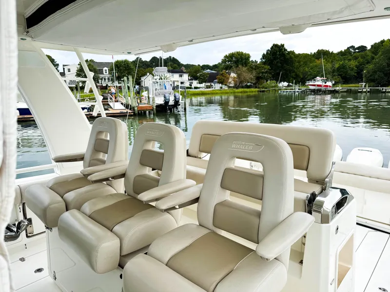 Slide: The Image of 2017 Boston Whaler 420 Outrage boat interior with luxurious seating, docked by a scenic waterfront. - 36