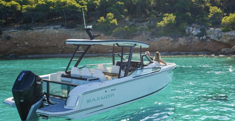 Slide: The Image of 2024 Saxdor 270 GTO boat on clear turquoise water near a rocky shoreline. - 1