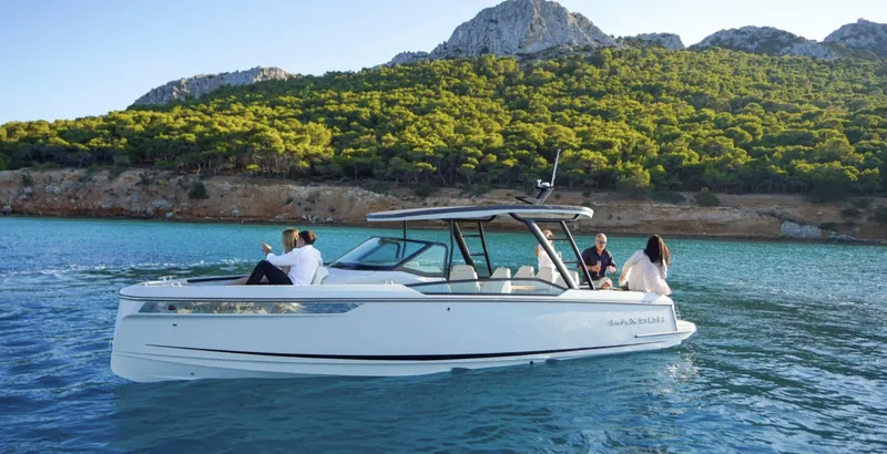 Slide: The Image of 2024 Saxdor 270 GTO boat cruising on scenic blue water near lush green hills. - 5