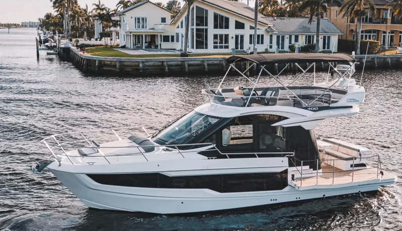 Slide: The Image of 2024 Galeon 400 Fly yacht cruising near waterfront homes. - 1