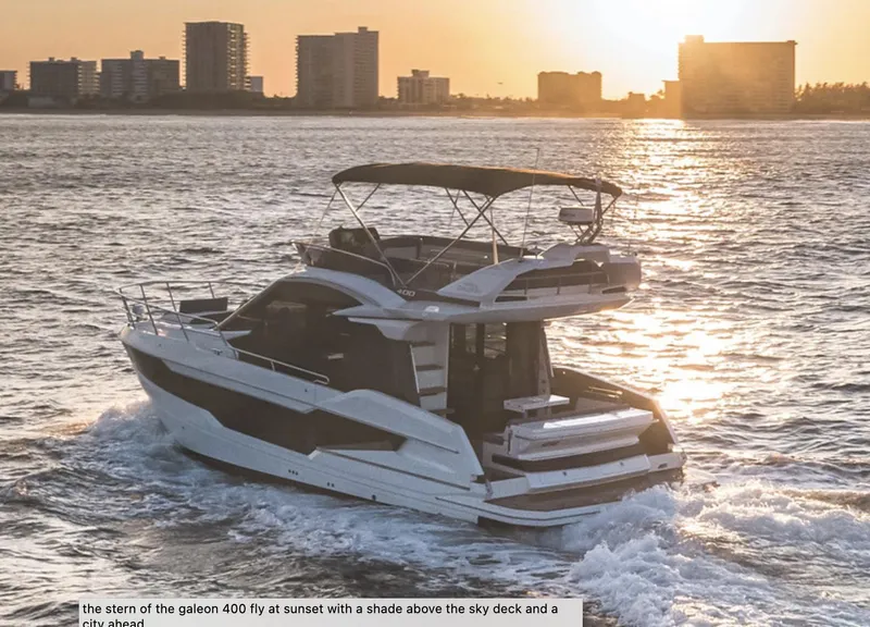 Slide: The Image of 2024 Galeon 400 Fly yacht cruising at sunset near city skyline. - 2