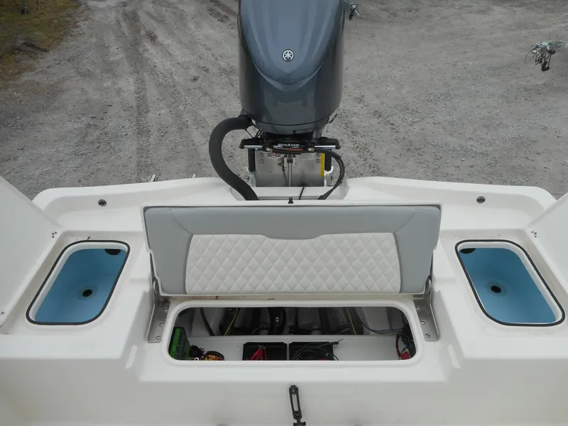 Slide: The Image of 2024 Avenger 26 Avenger boat with open storage compartments and outboard motor. - 9