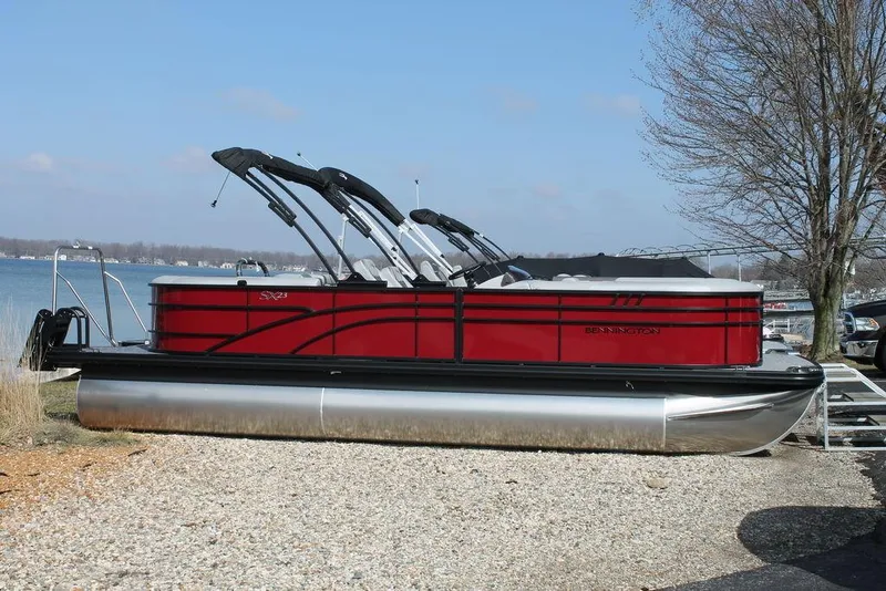 The Image of 2024 Bennington 23 SXSR pontoon boat in red, docked by a lake. - 1