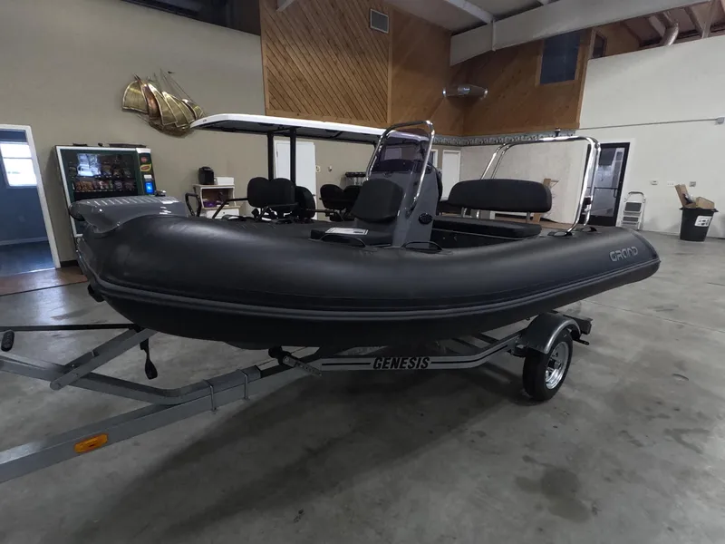 The Image of 2024 Grand Inflatables S370NL boat on Genesis trailer in indoor showroom. - 1