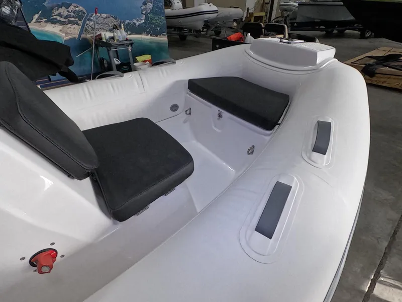 Slide: The Image of 2024 Grand Inflatables S370NL boat interior with black seating in a showroom. - 5