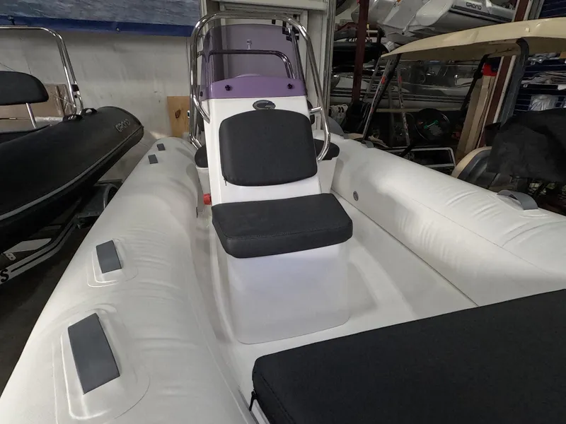 Slide: The Image of 2024 Grand Inflatables S370NL boat with white and black seating in a showroom. - 4