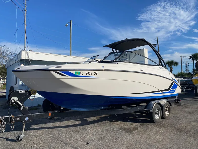 Slide: The Image of 2018 Yamaha Boats AR240 HO on trailer, white and blue, parked outdoors. - 0
