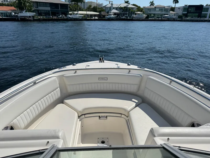 Slide: The Image of 2015 Robalo R247 Dual Console boat with spacious seating, docked near waterfront homes. - 16