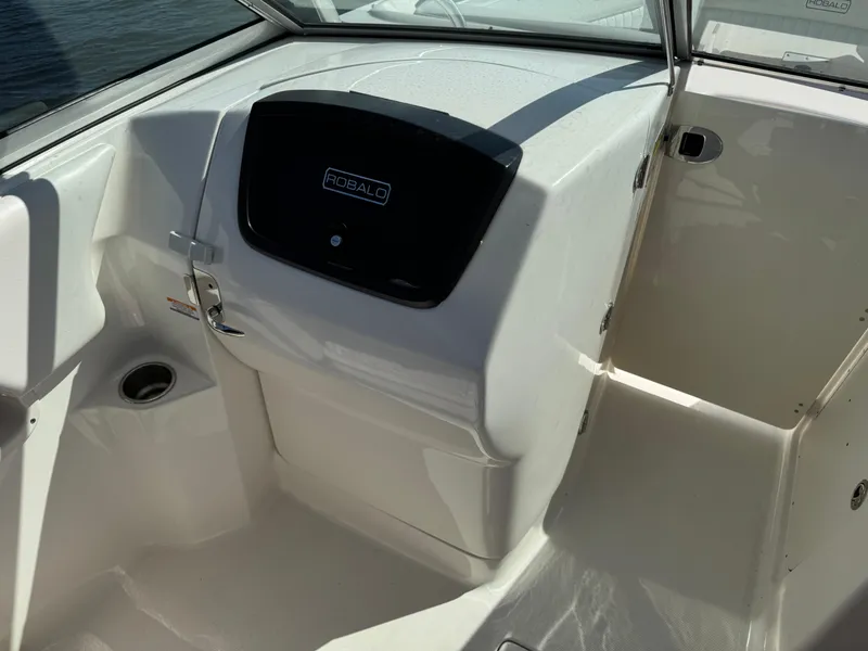 Slide: The Image of 2015 Robalo R247 Dual Console boat interior with sleek white design and storage compartment. - 17