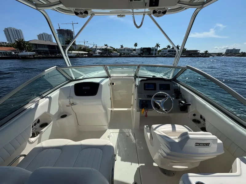 Slide: The Image of 2015 Robalo R247 Dual Console boat interior with steering wheel, seats, and waterfront view. - 19