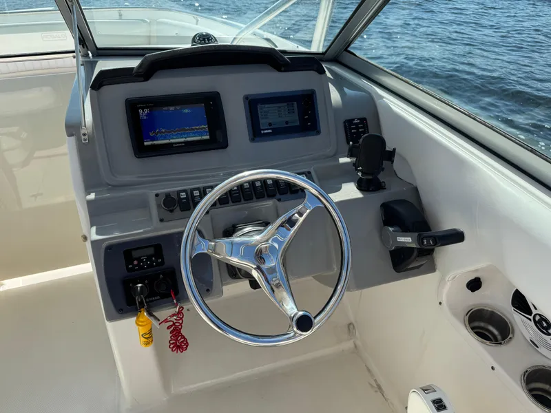 Slide: The Image of 2015 Robalo R247 Dual Console boat dashboard with steering wheel and navigation screens. - 20