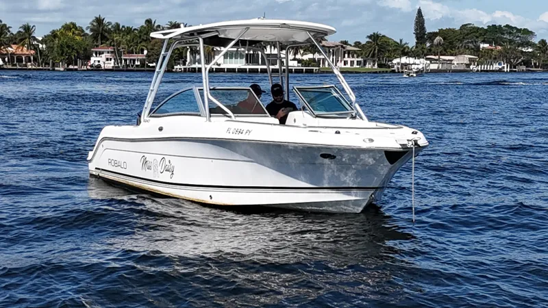 Slide: The Image of 2015 Robalo R247 Dual Console boat on calm water, near a coastal area. - 5