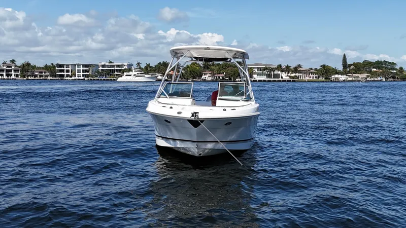 Slide: The Image of 2015 Robalo R247 Dual Console boat on calm water, with coastal buildings in the background. - 6