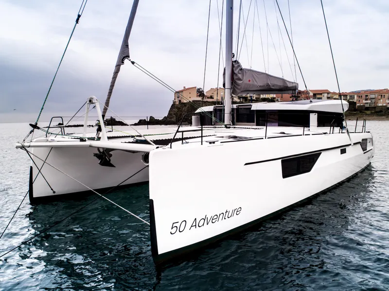 Slide: The Image of Windelo 50 Adventure 2025 catamaran anchored near coastal town. - 6