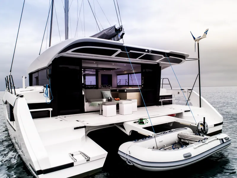 Slide: The Image of 2025 Windelo 50 Adventure catamaran with open deck and dinghy on calm sea. - 8