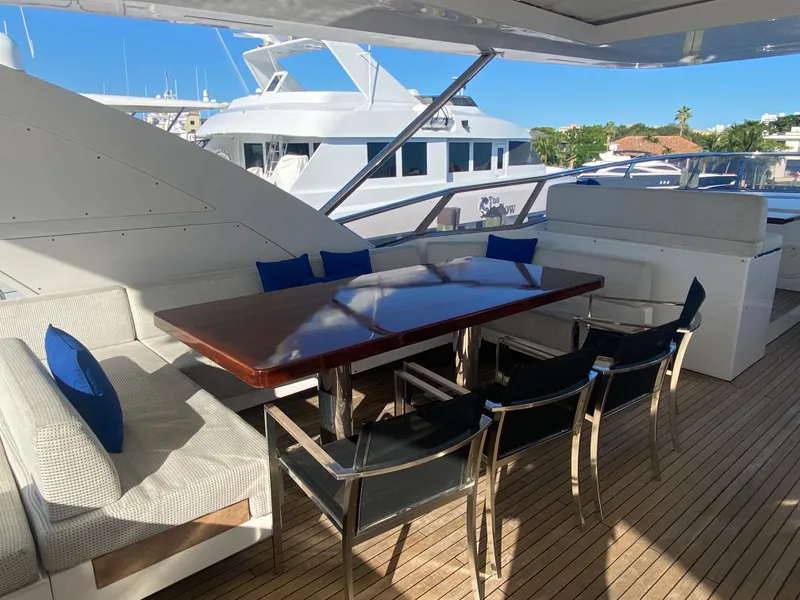 Slide: The Image of Outdoor dining area on 2014 Azimut 100 Grande yacht with wooden table and cushioned seating. - 41