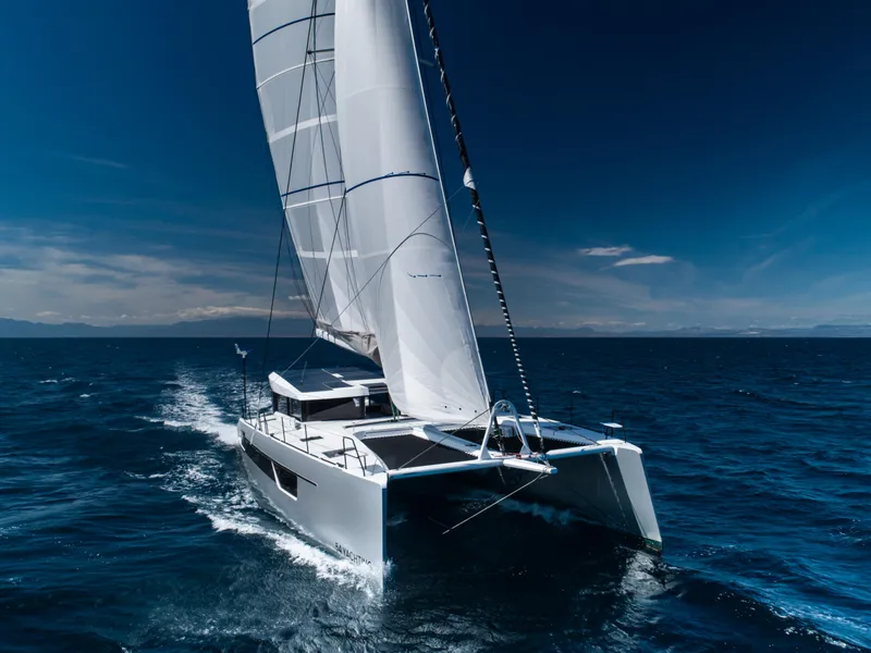 Slide: The Image of 2025 Windelo 54 catamaran sailing on open sea under clear blue sky. - 19