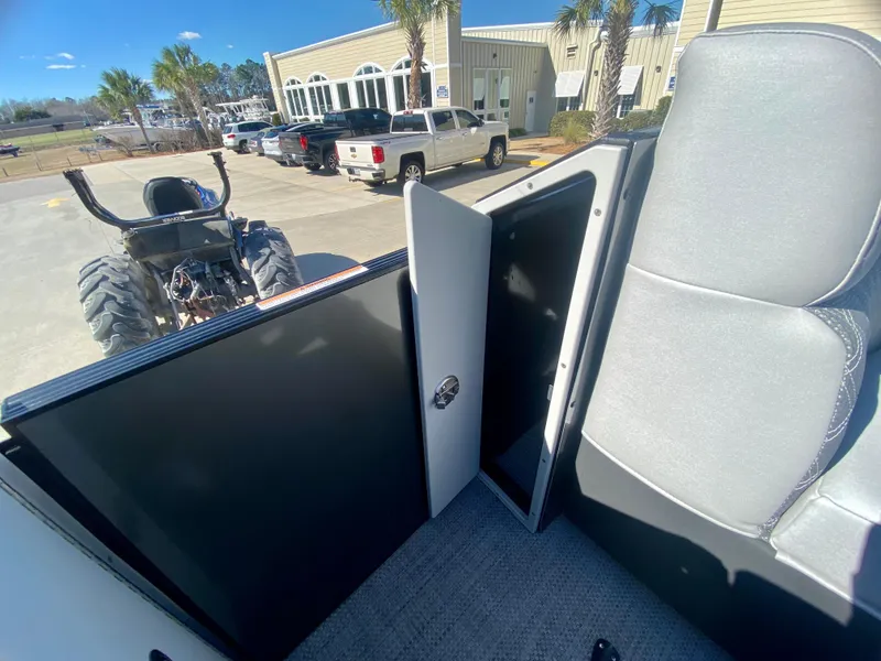 Slide: The Image of 2023 Vanderbilt 700T interior with open storage compartment, parked near trucks and buildings. - 26