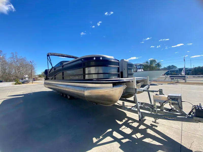 Slide: The Image of 2023 Vanderbilt 700T pontoon boat on a trailer under a clear blue sky. - 3