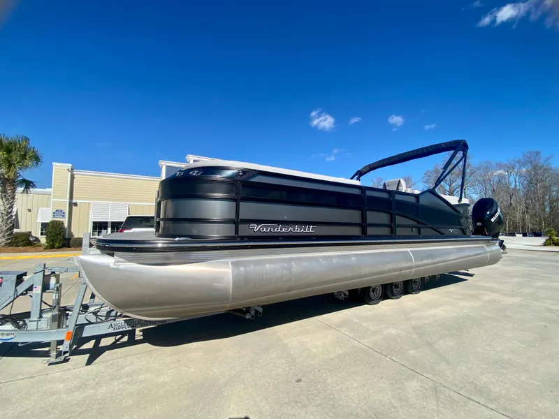 Slide: The Image of 2023 Vanderbilt 700T pontoon boat on a trailer under a clear blue sky. - 1