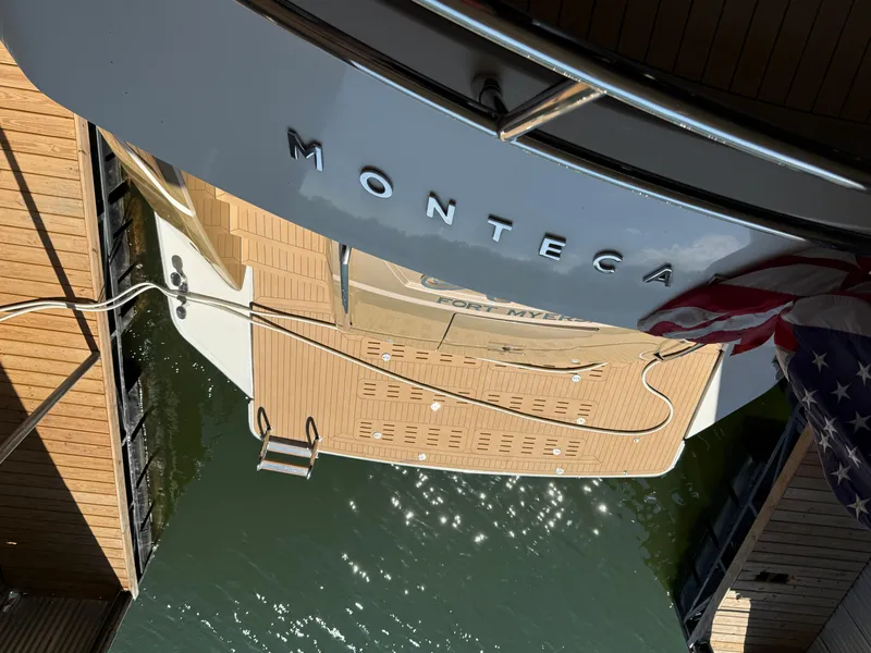 Slide: The Image of Monte Carlo Yachts 76, 2012 model, docked with American flag and water reflections. - 10
