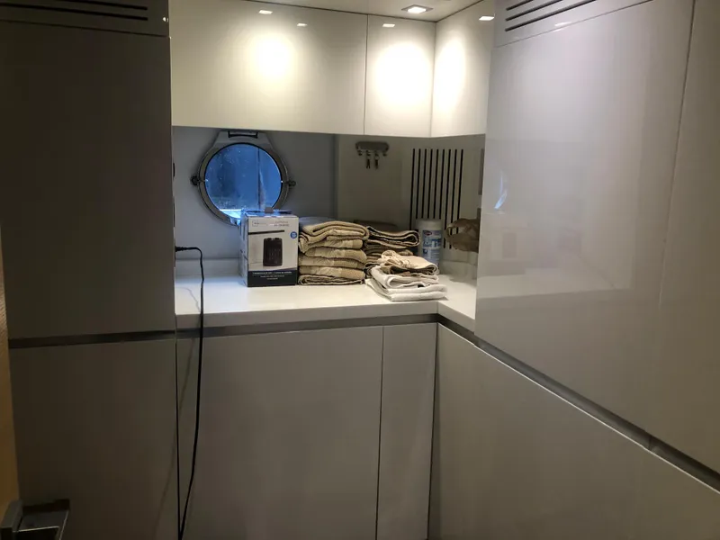 Slide: The Image of Modern laundry area on 2012 Monte Carlo Yachts 76 with porthole and stacked towels. - 20