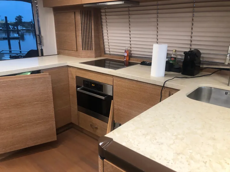 Slide: The Image of Modern kitchen interior on a 2012 Monte Carlo Yachts 76, featuring wood cabinetry and sleek countertops. - 31