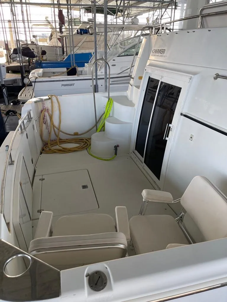 Slide: The Image of 2001 Carver 444 Cockpit Motor Yacht in marina, featuring spacious deck and seating. - 12