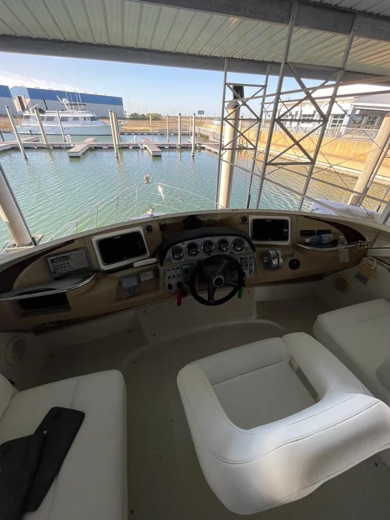 Slide: The Image of Interior view of 2001 Carver 444 Cockpit Motor Yacht helm with marina backdrop. - 28